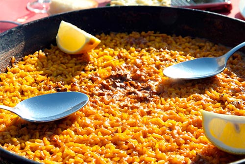 Arroz en una pellera con cucharas y rodajas de limón