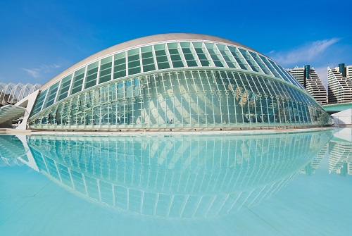 Edificio de metal y cristal con forma de ojo junto a un lago artificial