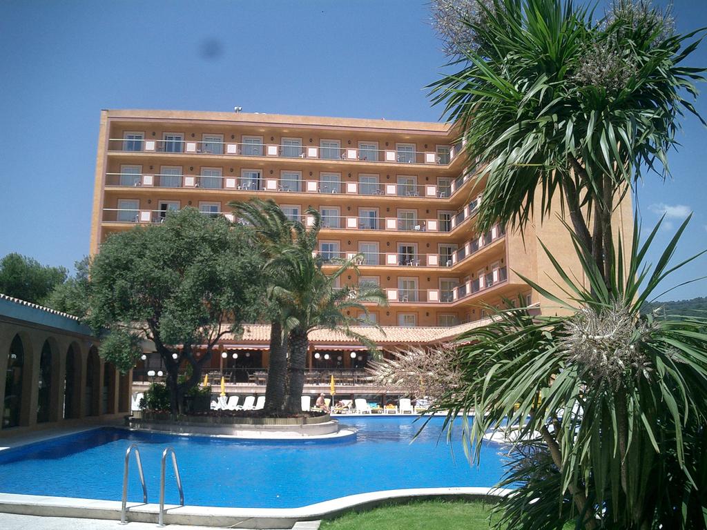 Fachada del hotel con la piscina y palmeras